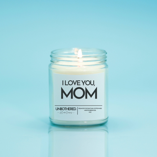 I Love You Mom Candle from the Unbothered Candle Co. Available in two Limited Edition Scents Pine Tree*, Holly Berry*, and two signature scents Cinnamon Roll and Vanilla Cookie. Vegan Soy Coconut Wax, 100% Cotton Wick, Hand-poured in the USA, Eco-friendly, non-toxic, no lead, no parabens, no synthetic dyes, no phthalates, and NEVER tested on animals.