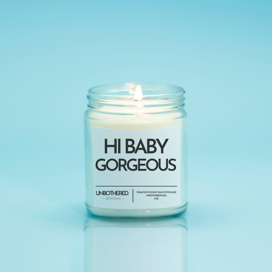 Hi Baby Gorgeous Candle from the Unbothered Candle Co. Available in two Limited Edition Scents Pine Tree*, Holly Berry*, and two signature scents Cinnamon Roll and Vanilla Cookie. Vegan Soy Coconut Wax, 100% Cotton Wick, Hand-poured in the USA, Eco-friendly, non-toxic, no lead, no parabens, no synthetic dyes, no phthalates, and NEVER tested on animals.