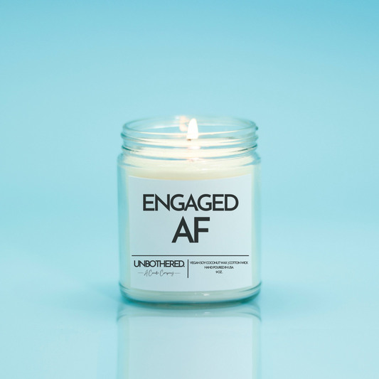 Engaged AF Candle from the Unbothered Candle Co. Available in two Limited Edition Scents Pine Tree*, Holly Berry*, and two signature scents Cinnamon Roll and Vanilla Cookie. Vegan Soy Coconut Wax, 100% Cotton Wick, Hand-poured in the USA, Eco-friendly, non-toxic, no lead, no parabens, no synthetic dyes, no phthalates, and NEVER tested on animals.